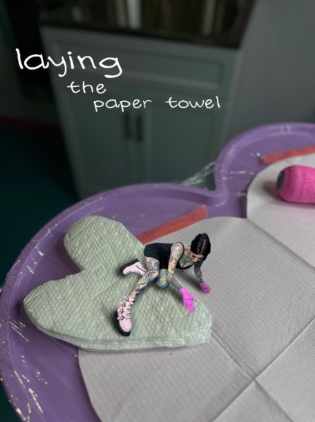 Mini Tia Berry figure laying the paper towel on her heart tattoo tray