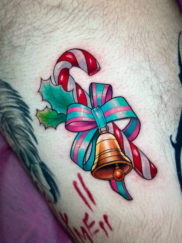 Candy cane and bell tattoo on the thigh by Tia Berry, colour tattoo artist in Vancouver
